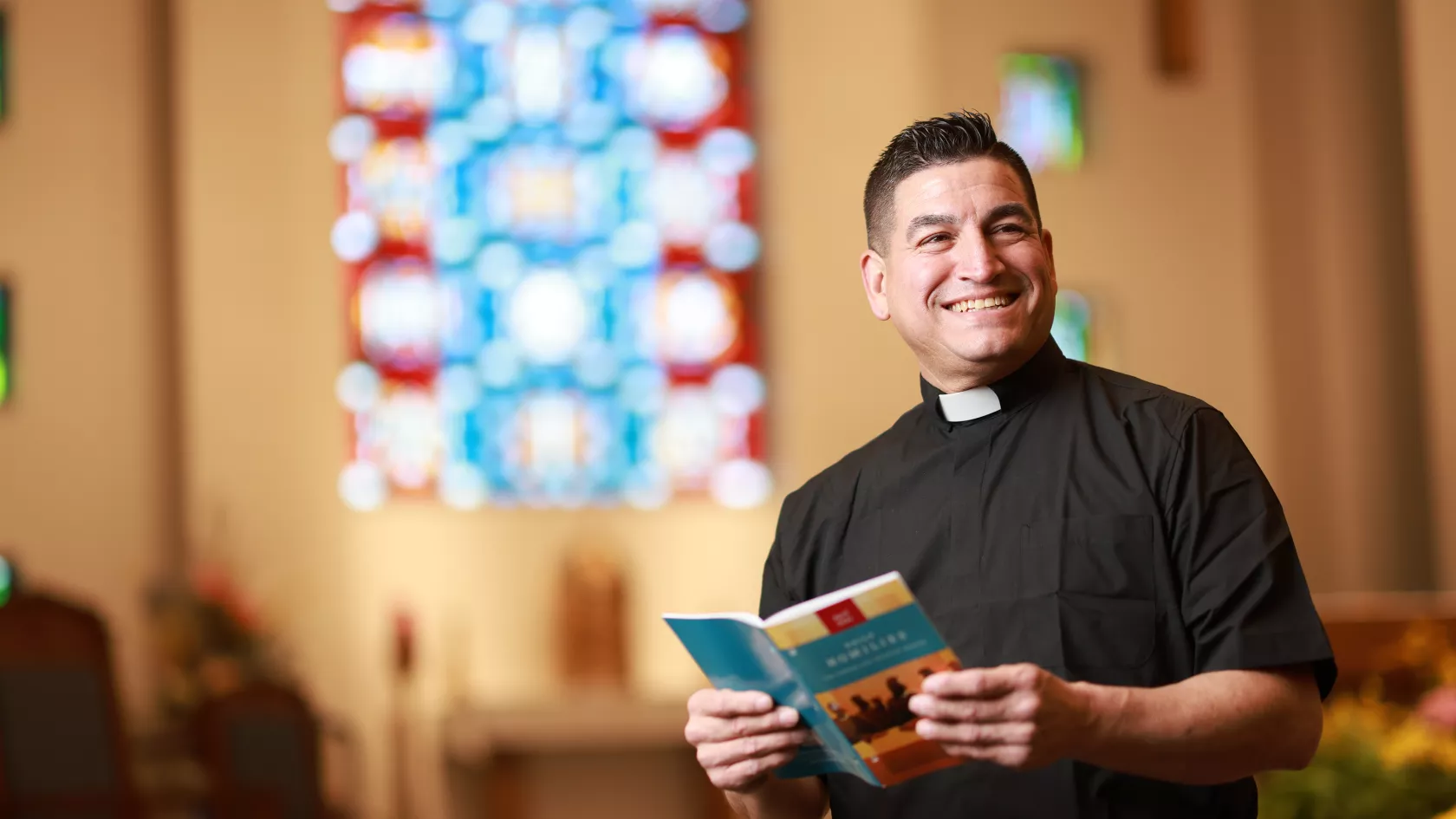 Priest holding Homilies Booklet